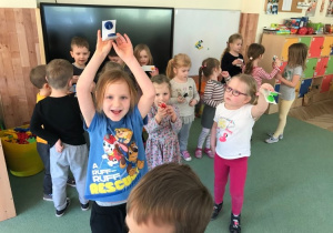 Uśmiechnięty Adaś prezentuje swoje kastaniety, w tle widoczne inne dzieci