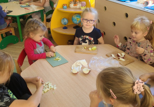 Adaś, Zuzia, dwie Amelki, Natalka i Kuba podczas krojenia jabłek przy stoliku
