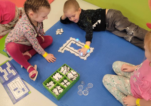 Zajęcia "Kodowanie na dywanie" - Kuba, Ala i Natalka wykonują zadanie - odpowiednie ułożenie puzzli