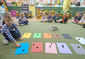 Leoś kładzie kasztan na kartce w kolorze niebieskim