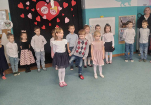 Julka, Olek i Justyna stoją na środku sali, recytują wiersze dla Babci i Dziadka