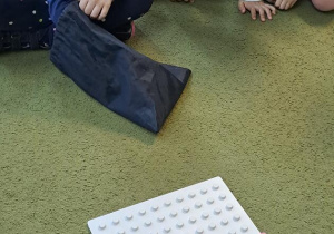 Hania szuka w worku za pomocą dotyku odpowiedniego kształtu do ułożonych korali na podstawie
