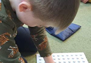 Mateusz sprawdza czy wylosowany kształt pasuje do tego ułożonego z korali na podstawie