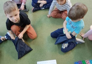 Antoś i Filip szukają w workach za pomocą dotyku odpowiednich kształtów do ułożonych korali na podstawie