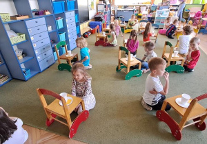 Dzieci układają sylwety herbatników po lewej stronie kubków z herbatą