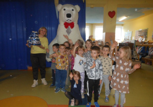 Grupa delfinków pozuje z dużym misiem.