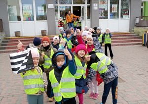 Dzieci po spektaklu czekają przed szkołą w odblaskowych kamizelkach