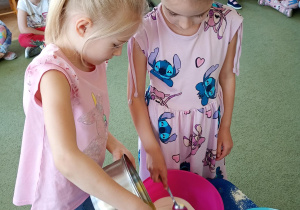 Dziewczynki dodają rozpuszczone masło do ciasta