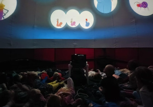 Dzieci leżą i oglądają film w Planetarium mobilnym