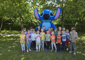 Grupowe zdjęcie Misiów z dużą maskotką Stitcha.