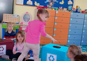 Hania wrzuca odpad do niebieskiego pojemnika.