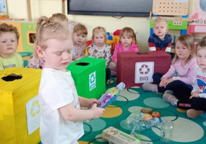 Michalina wrzuca butelke plastikową do odpowiedniego pojemnika.