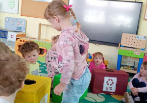 Sara wrzuca odpad do żółtego pojemnika.