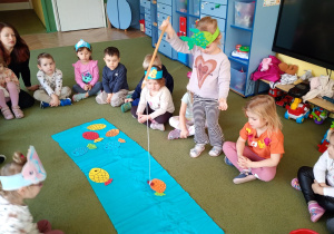 Dziewczynka łowi na wędkę papierową sylwetę ryby