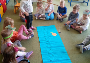 Dziewczynka łowi na wędkę papierową sylwetę ryby