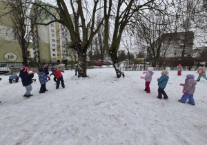 Dzieci trenują rzuty śnieżkami celując w drzewa