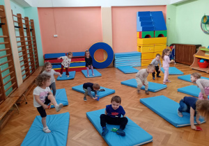 Maluszki przekładają woreczki pod nogami w pozycji stojącej