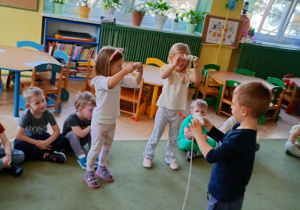 Maluszki nawlekają marchewki na rolki, naśladując jedzące warzywa słonie