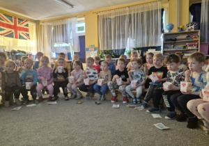Dzieci oglądają bajkę jedząc popcorn