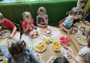 Dzieci jedzą pyszne szaszłyki owocowe