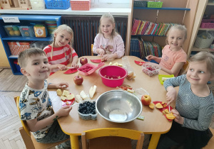Dzieci ze stolika żółtego kroją owoce