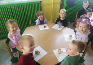 Dzieci przy zielonym stoliczku z ciastem śliwkowym