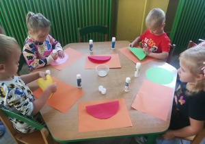 Dzieci przy zielonym stoliku tworzą pracę plastyczną "Bajkowy samochód"