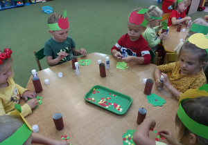 Dzieci przy zielonym stoliku tworzą jabłonki