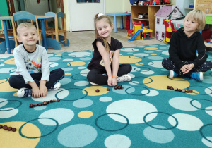 Julka, Damian i Jaś siedzą na dywanie podczas zajęć