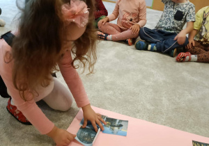 Dziewczynka przykleja obrazki do plakatu