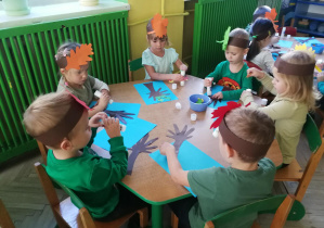 Dzieci przy zielonym stoliku tworzą "Jesienne klony"