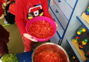 Mateusz wsypuje pokrojone pomidory do garnka