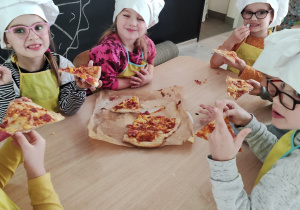 Dzieci jedzą samodzielnie zrobioną pizzę