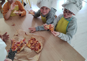 Dzieci jedzą samodzielnie zrobioną pizzę
