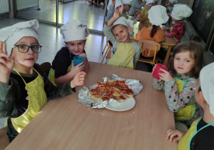 Dzieci jedzą samodzielnie zrobioną pizzęw