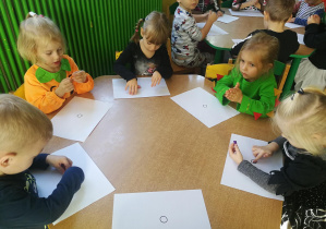 Dzieci przy żółtym stoliku wyklejają plasteliną wzory "kropek/plamek"