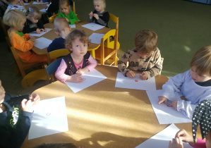Dzieci przy niebieskim stoliku wyklejają plasteliną wzory "kropek/plamek"