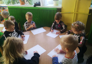 Dzieci przy zielonym stoliku wyklejają plasteliną wzory "kropek/plamek"
