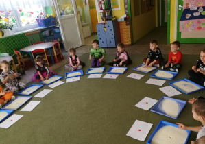Dzieci wystukują na tackach z kaszą manną rytm piosenki "Ja i ty", tworząc kropki