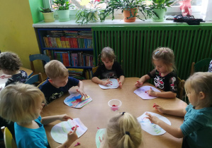 Dzieci tworzą na swoich fartuszkach wzory kropek/plamek palcami umoczonymi w farbie w rytmie piosenki "Ja i ty"