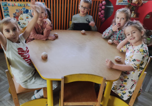 Dzieci jedzą przy stolikach słodki poczęstunek