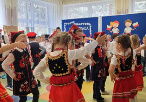 Dzieci ubrane w tradycyjne stroje tańczą krakowiaka