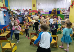 Przedszkolaki maszerują pomiędzy krzesłami i wystukują rytm