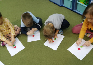 Dzieci wystukują na wzorach dwóch pionowych kropek rytm piosenki "Kolorowe światła"