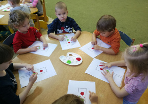 Dzieci świewają i rytmizują piosenkę, tworząc dwie pionowe kropki z farby