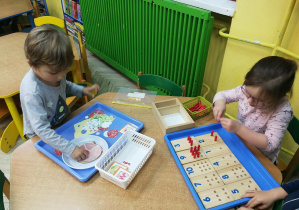Dzieci pracują z montessoriańskim materiałem rozwojowym: "Tabliczki liczbowe i kołeczki", "Kanapka"