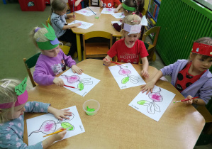Przedszkolaki przy zielonym stoliku malują farbą liście buraków