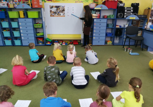Dzieci wraz z nauczycielką wystukują rytm rymowanki w zabawie "Idzie, idzie miś"