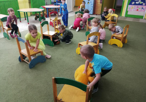 Dzieci kładą pluszaki "pod" krzesłami