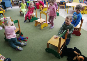 Dzieci kładą pluszaki "za" krzesłami